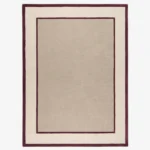 Studio flat-lay product photograph of the rectangular The Frame rug on a clean background, showcasing the neutral beige wool field framed by bold maroon-red inner and outer border lines.