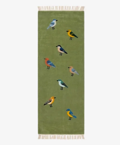 Full overhead studio flat lay of the green Woodland Chorus runner rug featuring a playful pattern of multi-colored birds and finished with white fringe ends.